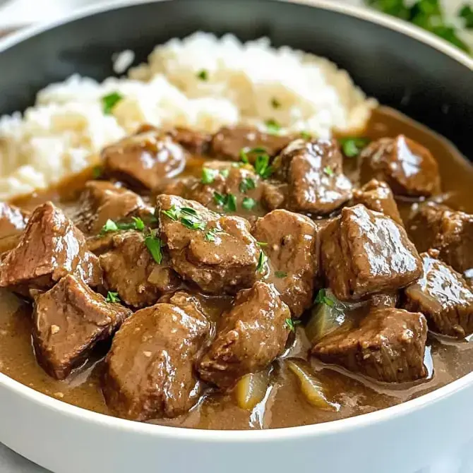 Un plat de viande en sauce avec des morceaux de viande tendre accompagnés de riz blanc.