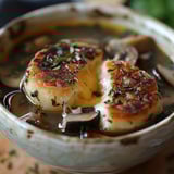 A bowl of soup with mushrooms and bread.