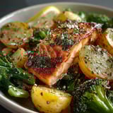 A bowl of food containing broccoli, potatoes, and salmon.