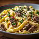 A bowl of pasta with meat and herbs.