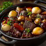 A pot of beef bourguignon with mushrooms and onions.