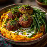 A bowl of food with falafels, patate douce and haricots.