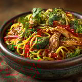 A bowl of noodles with chicken and broccoli.