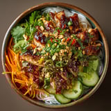 A bowl of food with meat and vegetables.