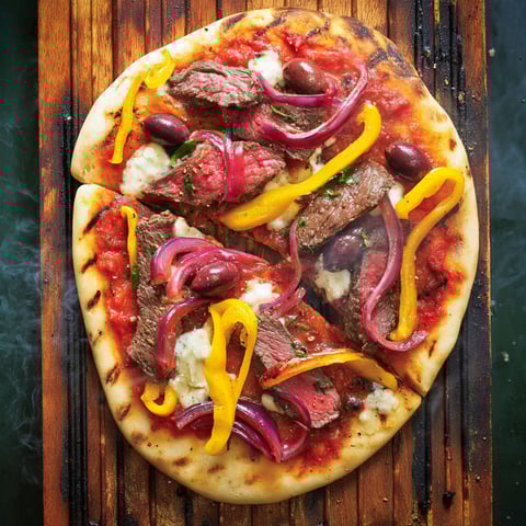 A pizza with meat and vegetables on it.