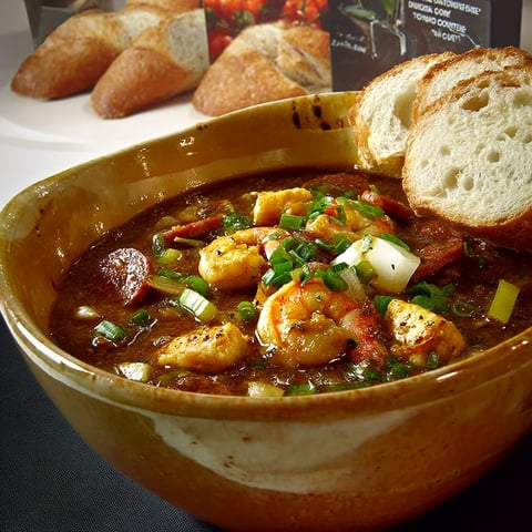 A bowl of gumbo with shrimp and vegetables.